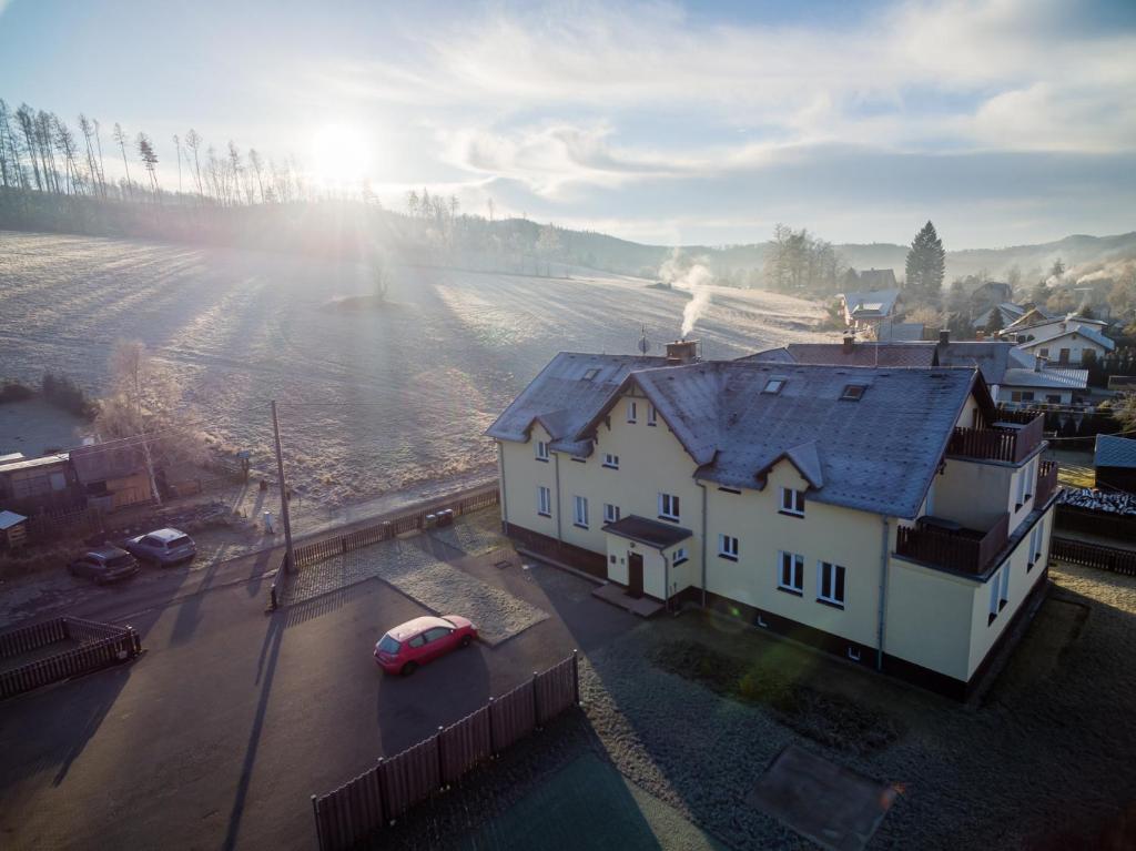 a white house with a red car in a field at Apartmán Jasmína v Jeseníkách in Karlovice