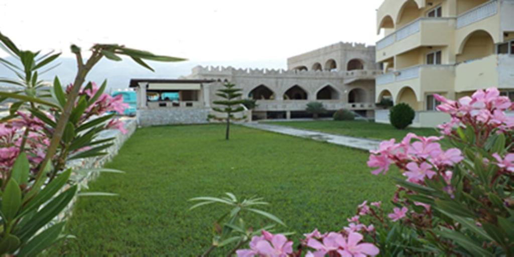 a large building with a yard with pink flowers at Castle Hotel in Himare