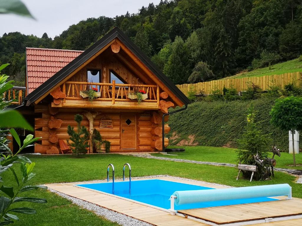 une cabane en rondins avec une piscine en face de celle-ci dans l'établissement Forest Glade Cottage - Koča na jasi, à Rečica ob Savinji