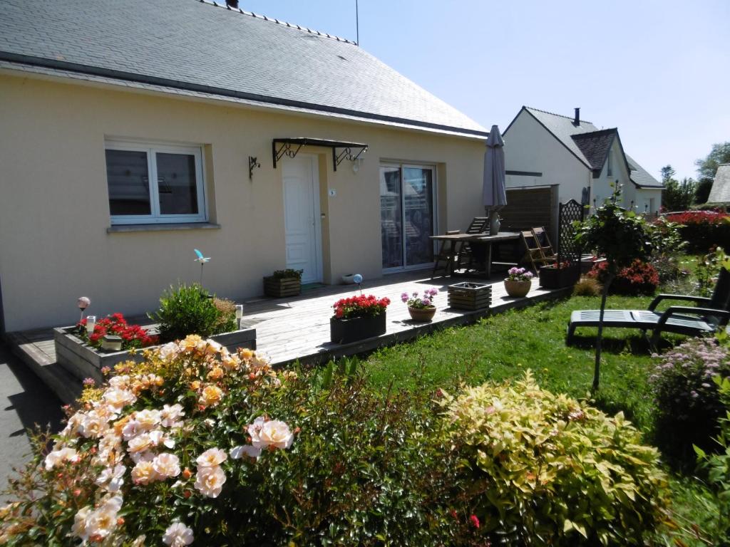 a house with a wooden deck with flowers in the yard at Maison d'Hôtes La Marie Pierre in Pluherlin