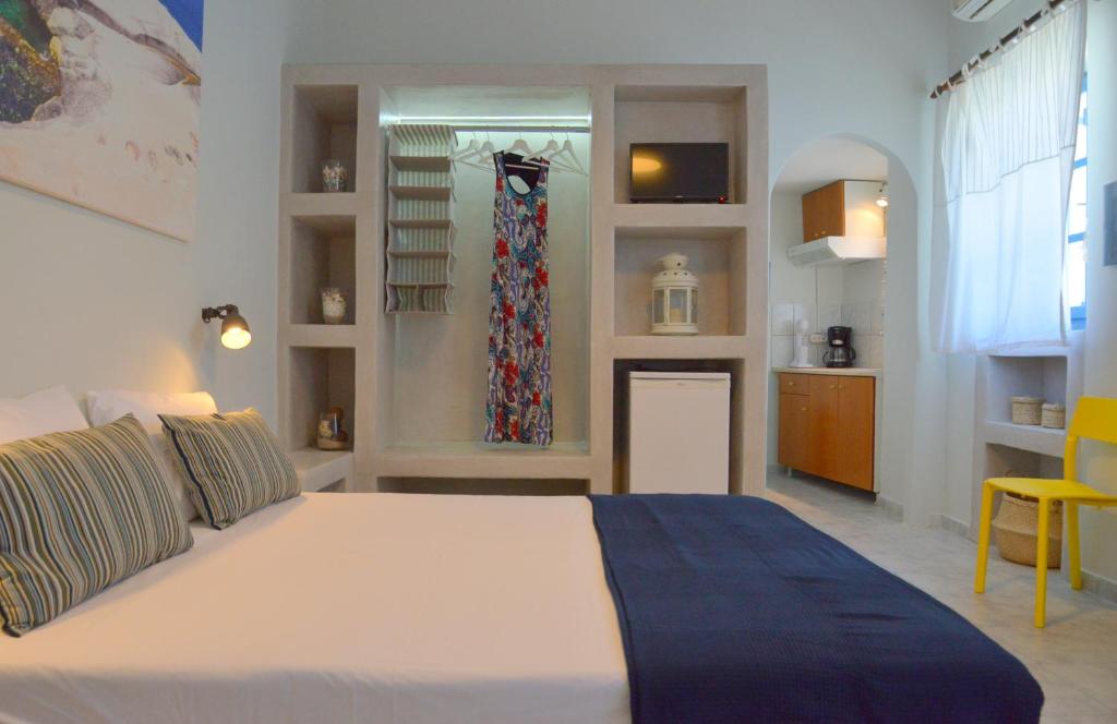 a bedroom with a large white bed and a kitchen at Tsakonas Plakes Studios in Plaka Milou