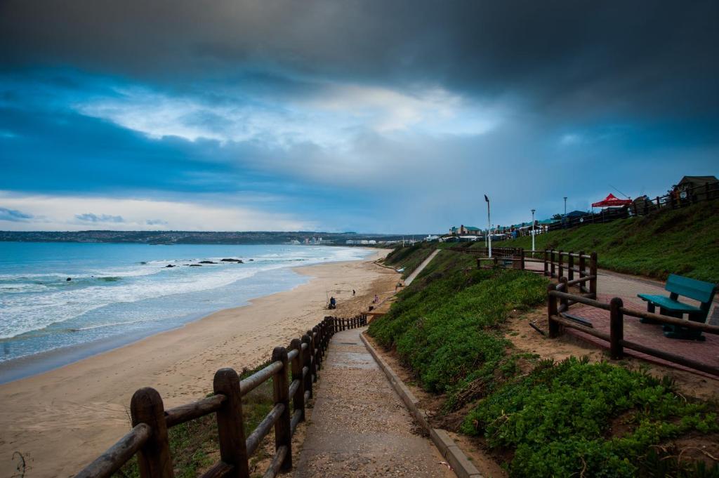 uma praia com bancos e o oceano num dia nublado em ATKV Hartenbos em Hartenbos