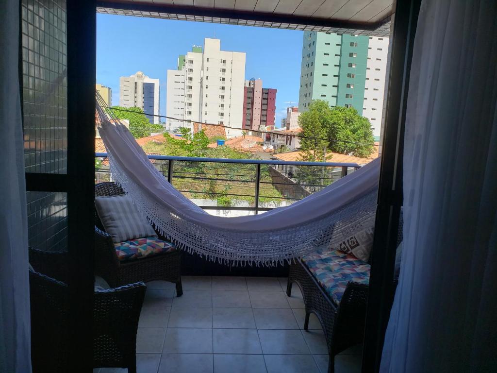 un balcón con hamaca y vistas a la ciudad en Apartamento na praia de Manaira, en João Pessoa