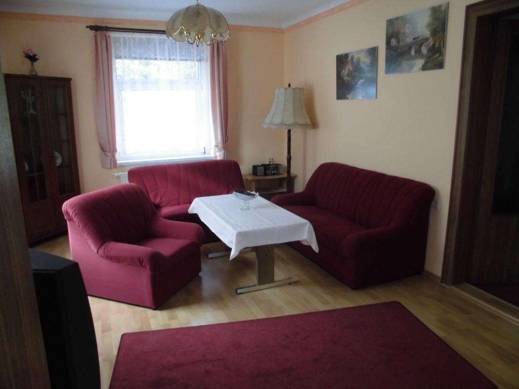 Sala de estar con 2 sillas rojas y mesa de centro en Ferien-bei-Seifert en Dresden