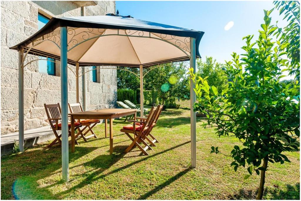 una mesa y sillas bajo una sombrilla en un patio en 3 bedrooms house with private pool enclosed garden and wifi at Carballedo, en Carballedo