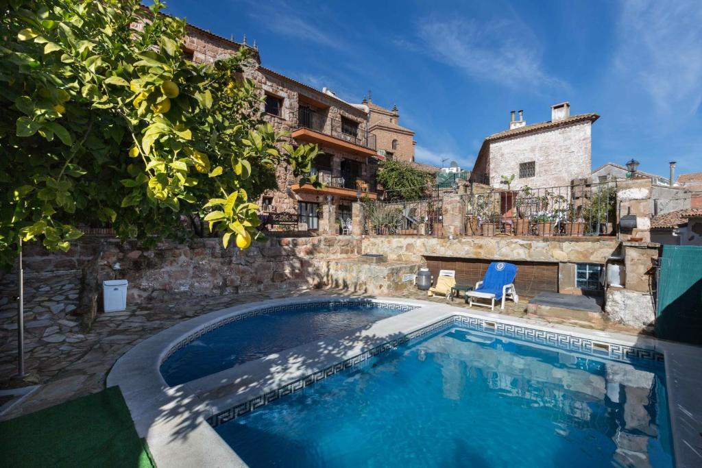 a swimming pool in a yard with a building at Hotel Palacio Guzmanes in Baños de la Encina