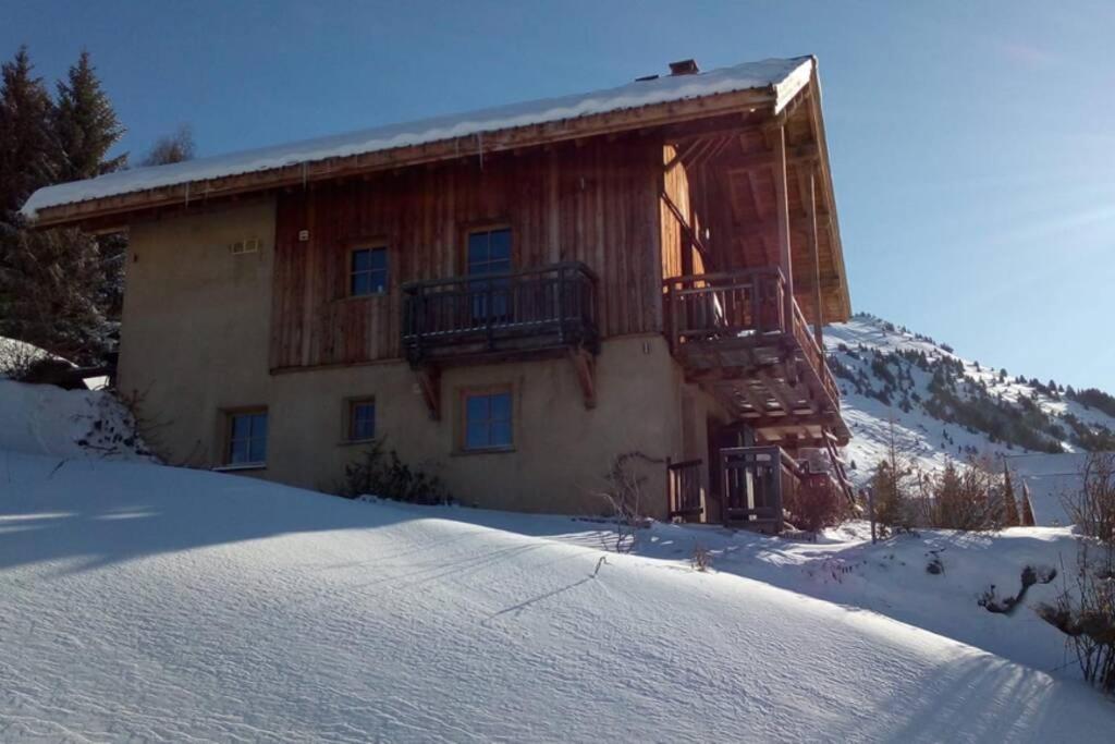 une cabane en rondins dans la neige avec un balcon dans l'établissement Chalet 4* hammam sauna jacuzzi panorama, à Villard-Reculas