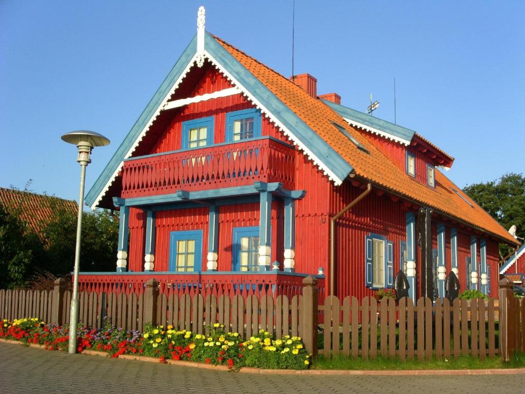 una casa roja con una valla delante en Inkaro Kaimas, en Nida