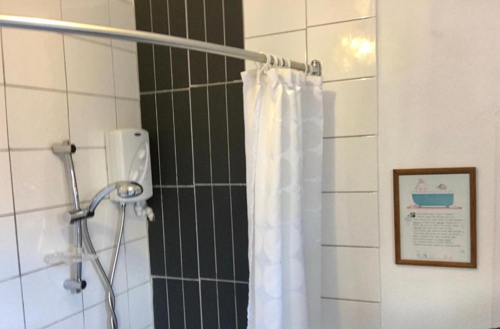 a shower with a white shower curtain in a bathroom at Lavender Apartment in Leicester