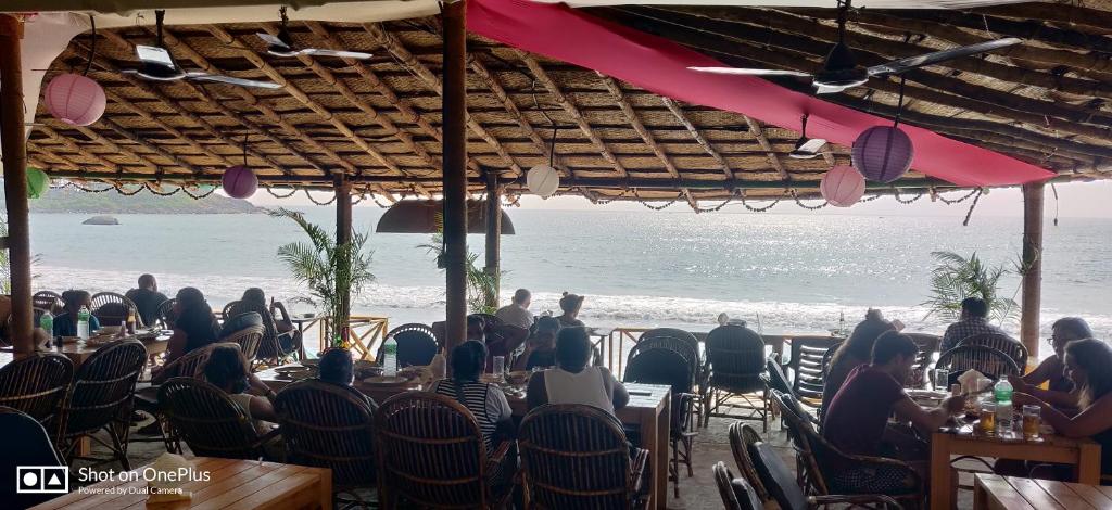 a group of people sitting at tables on the beach at Rococo Pelton beach huts Palolem Beach goa in Palolem