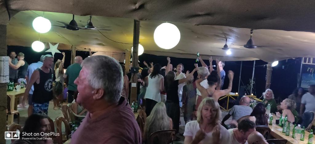 a crowd of people sitting in a bar with their hands in the air at Rococo Pelton beach huts Palolem Beach goa in Palolem