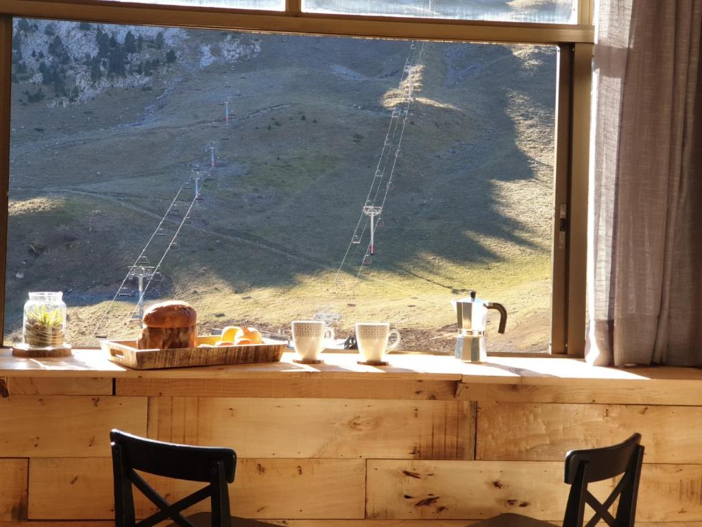 a window with a table with food and a view of a mountain at Apartamento El sarrio in Candanchú