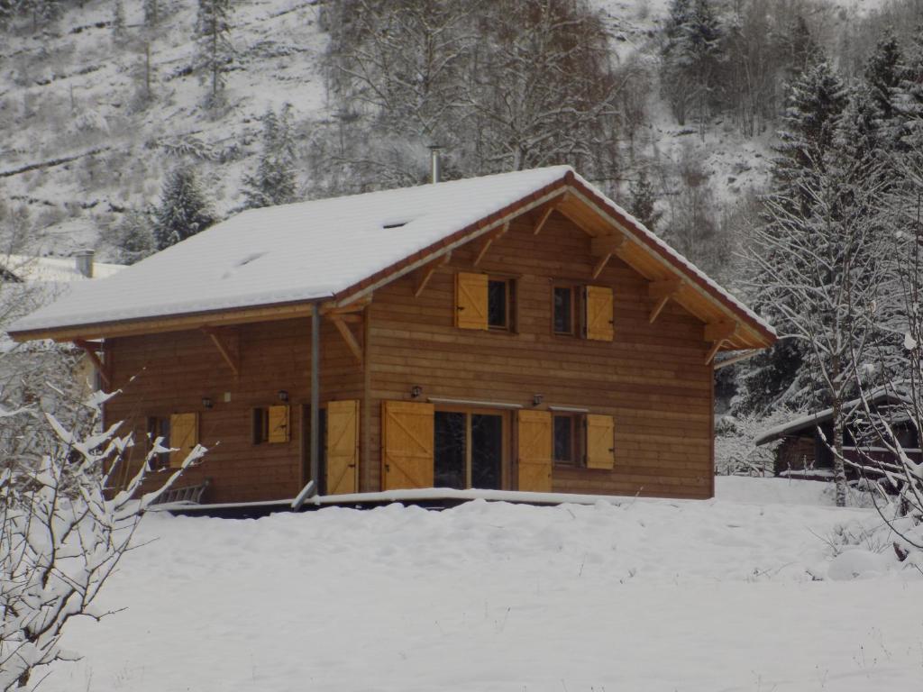uma casa de madeira com neve em cima em CHALET DES CHARBONNIERS AVEC ETANG em Saint-Maurice-sur-Moselle