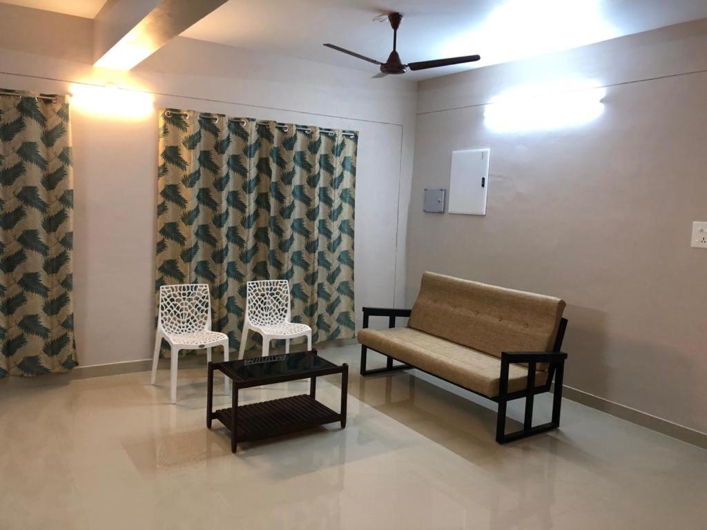 una sala de espera con 2 sillas y un sofá en Nachiyar Suites en Thiruvananthapuram