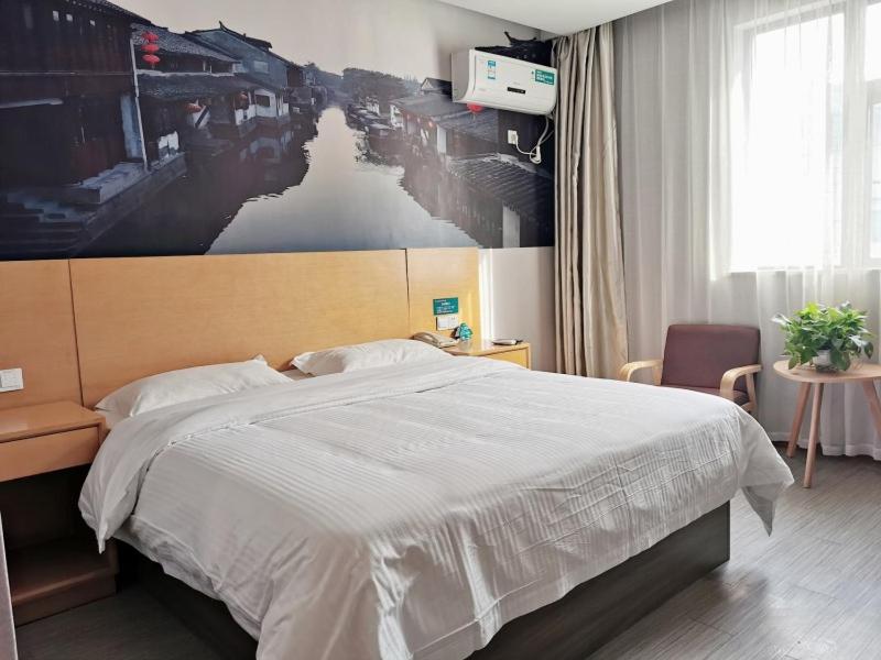 a bedroom with a bed with a large picture on the wall at GreenTree Inn JiangSu SuZhou International Film City South JinShan Road Express Hotel in Suzhou