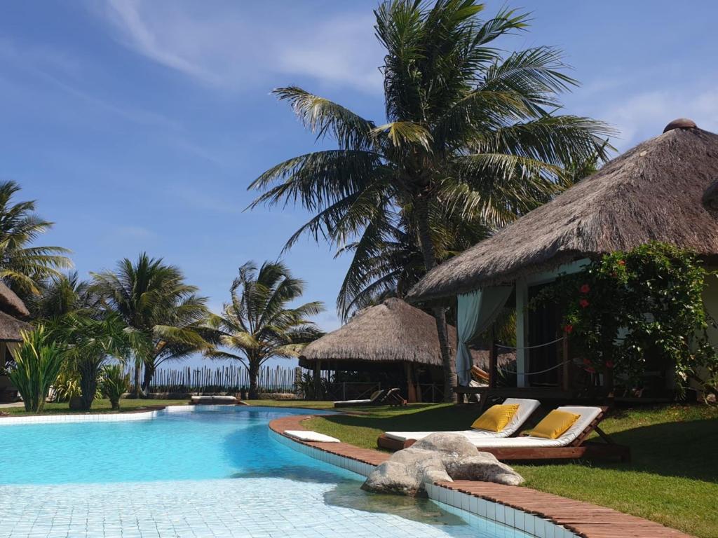 um resort com uma piscina com cadeiras e palmeiras em Pousada Residencia Duna Paraiso em Maceió