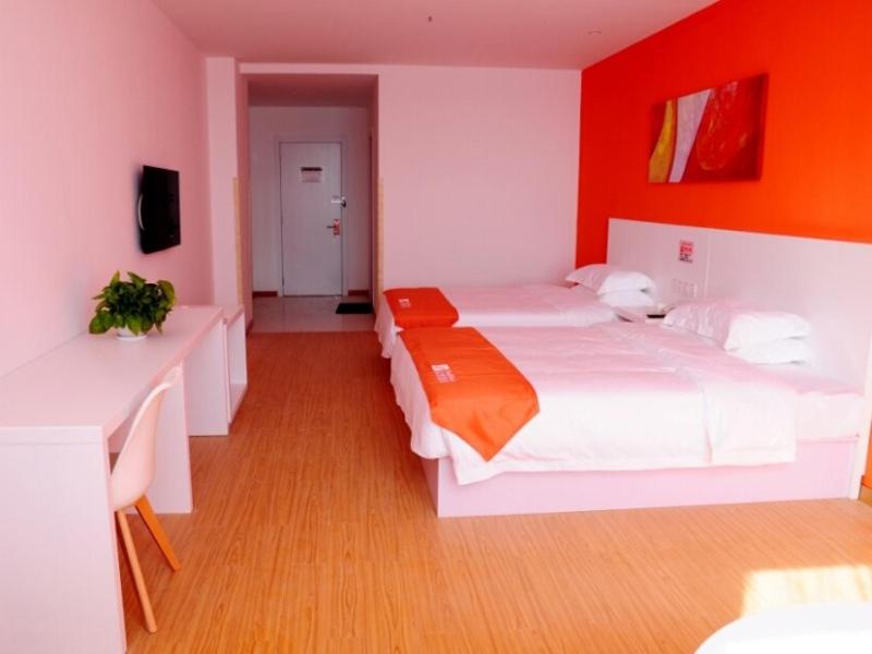 a bedroom with two white beds and an orange wall at Shell Shangxi Xinzhou Dai County 108 State Road Hotel in Dai