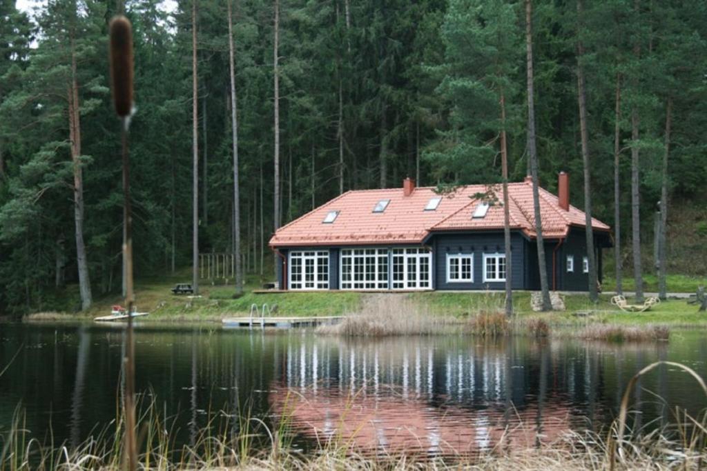 una casa con techo rojo junto a un lago en Saulės Slėnis, en Plateliai