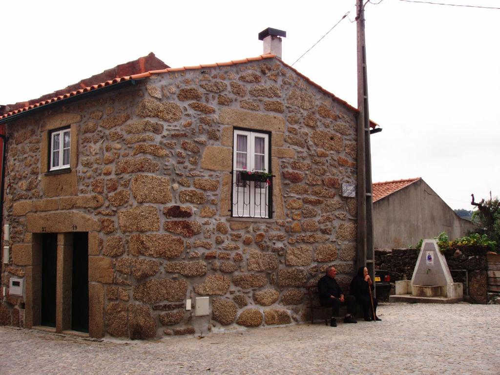 two people sitting outside of a stone building at Casa d'avó Maria in Seia