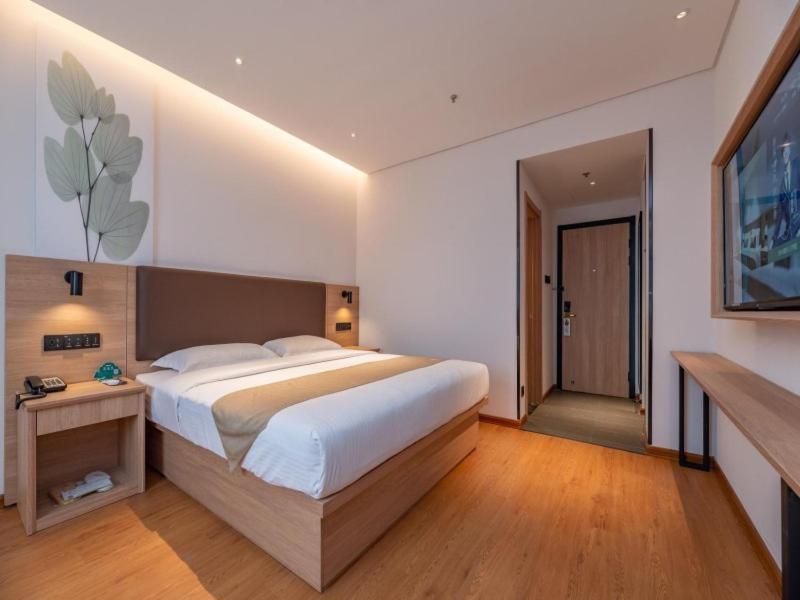 a bedroom with a large bed and a television at GreenTree Inn Ji‘nan Shanda Road Business Hotel in Jinan