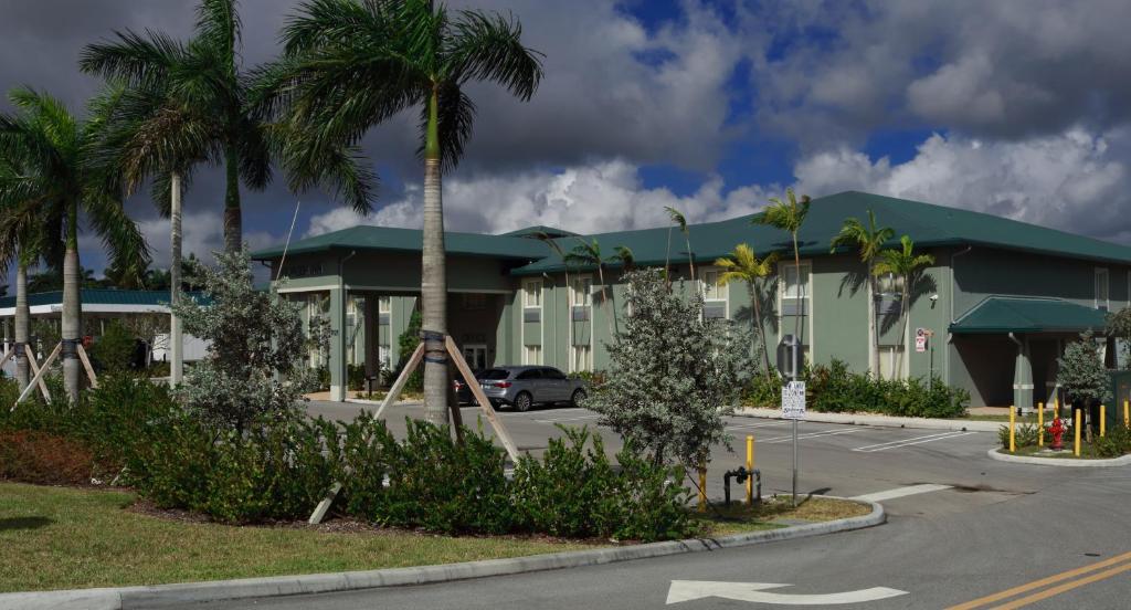 a building with palm trees in front of a parking lot at Pioneer Inn in West Palm Beach