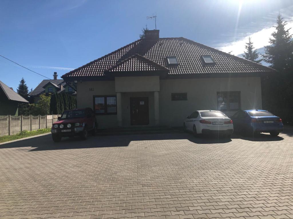 una casa con dos coches estacionados frente a ella en Klimatyzowane Apartamenty i Pokoje przy Targach Kielce, en Kielce
