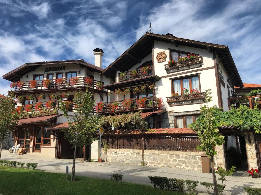 ein großes weißes Gebäude mit vielen Fenstern und Balkonen in der Unterkunft Family Hotel Dzhangal in Bansko