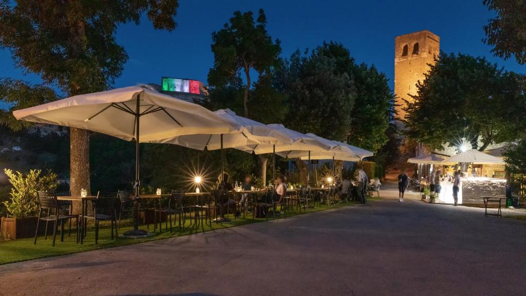 un grupo de mesas con sombrillas en un parque por la noche en Osteria Belvedere, en San Leo