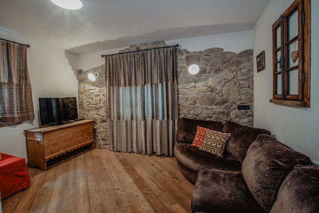 salon ze skórzaną kanapą i kamienną ścianą w obiekcie Pradella Apartments w mieście Valdidentro