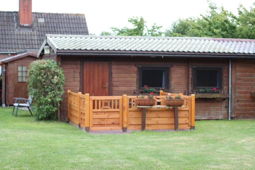 a wooden fence in front of a cabin at Haus Seerobbe-Blockhaus im Garten in Fehmarn