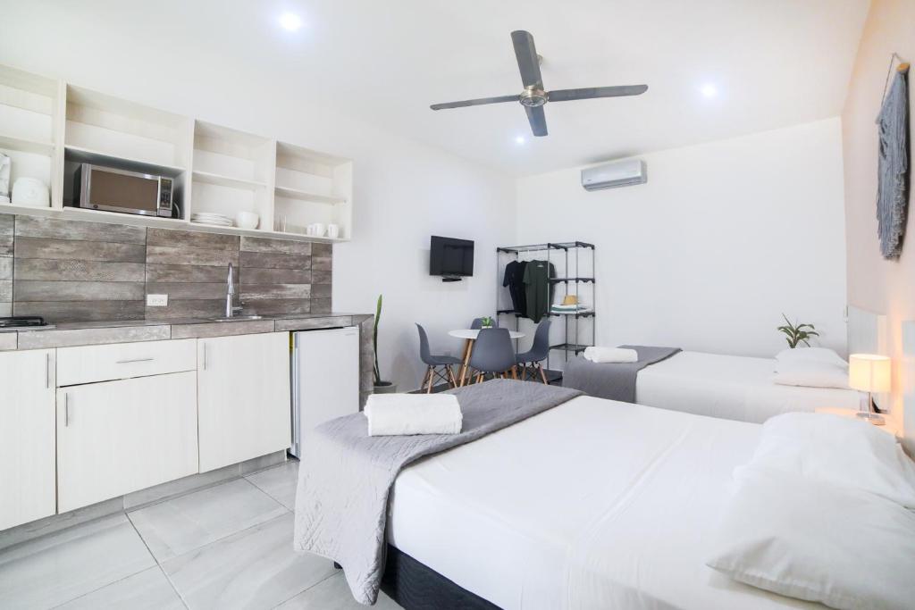 Habitación blanca con cama y cocina en Almond Suites en Playa del Carmen