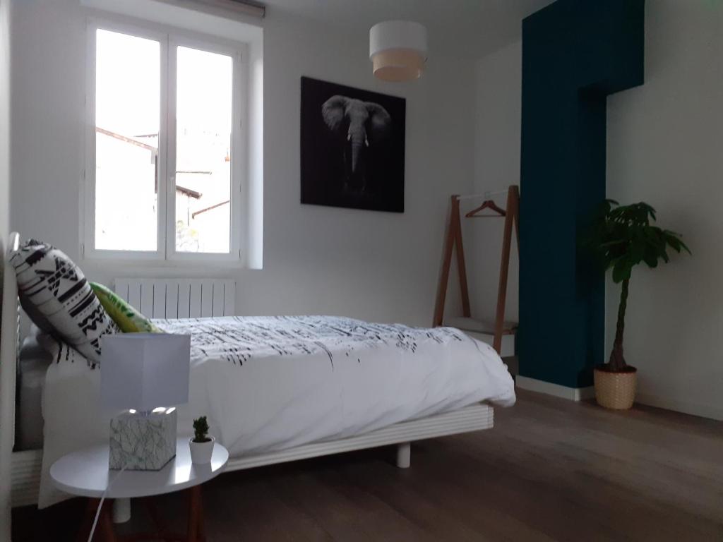 - une chambre blanche avec un lit et une fenêtre dans l'établissement Tropical loft, au Puy-en-Velay