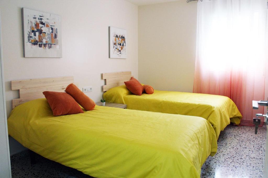2 Betten in einem Zimmer mit gelber Bettwäsche in der Unterkunft Casa Albeniz. in Algeciras