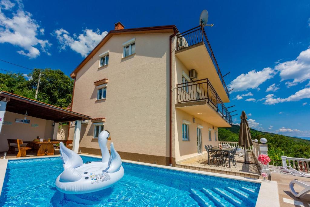 a swimming pool with an inflatable swan in front of a house at House Villa Andrea in Crikvenica
