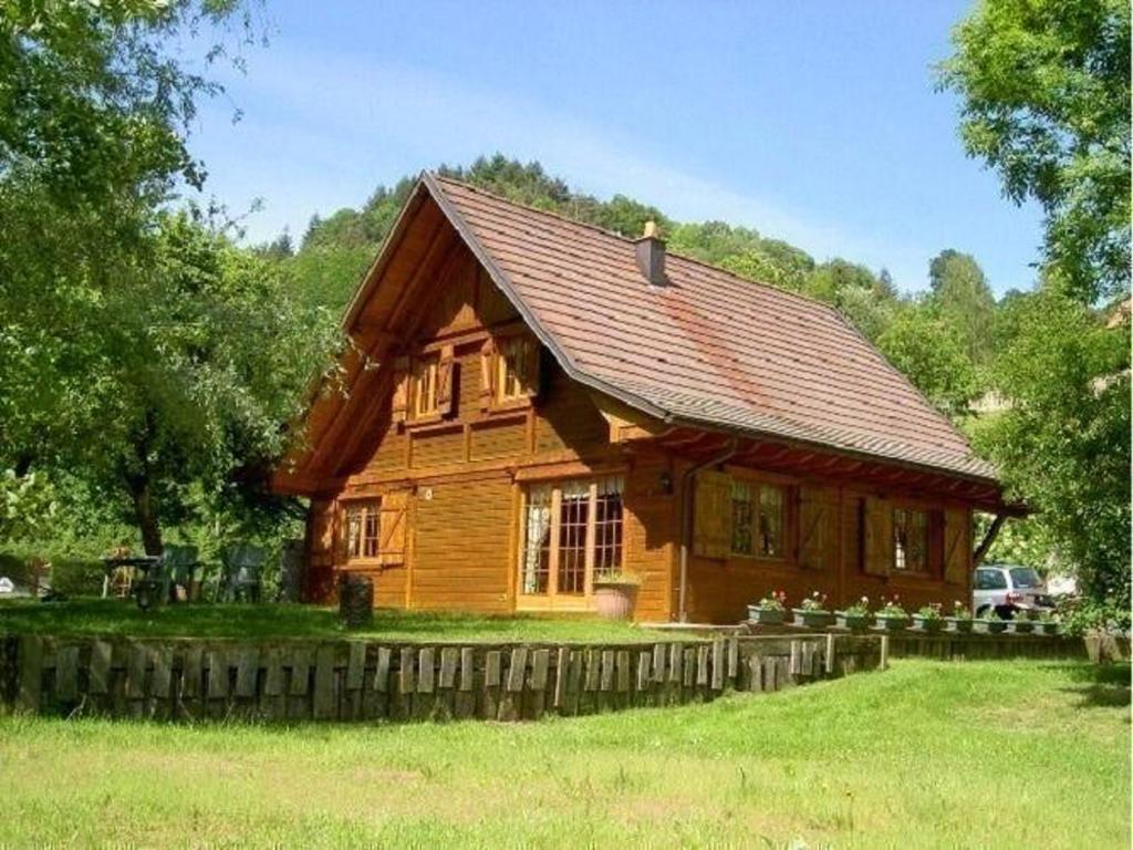 een houten hut in een veld met bomen op de achtergrond bij Chalet de 4 chambres avec jardin amenage a Lalaye in Lalaye