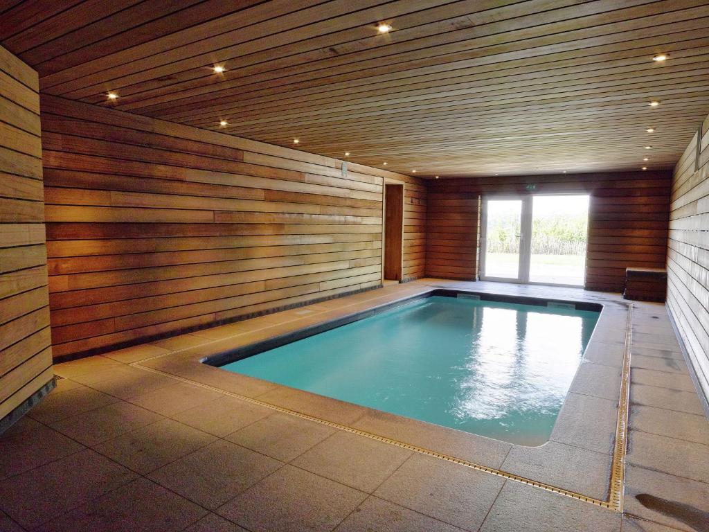 ストゥモンにあるComfortable chalet with indoor pool hammam and sauna near Stoumontの木製の壁の客室内のスイミングプール