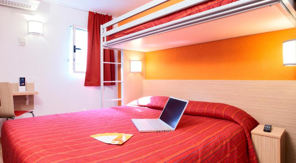 um quarto com uma cama com um computador portátil em Premiere Classe Marne La Vallee - Saint Thibault Des Vignes em Saint-Thibault-des-Vignes