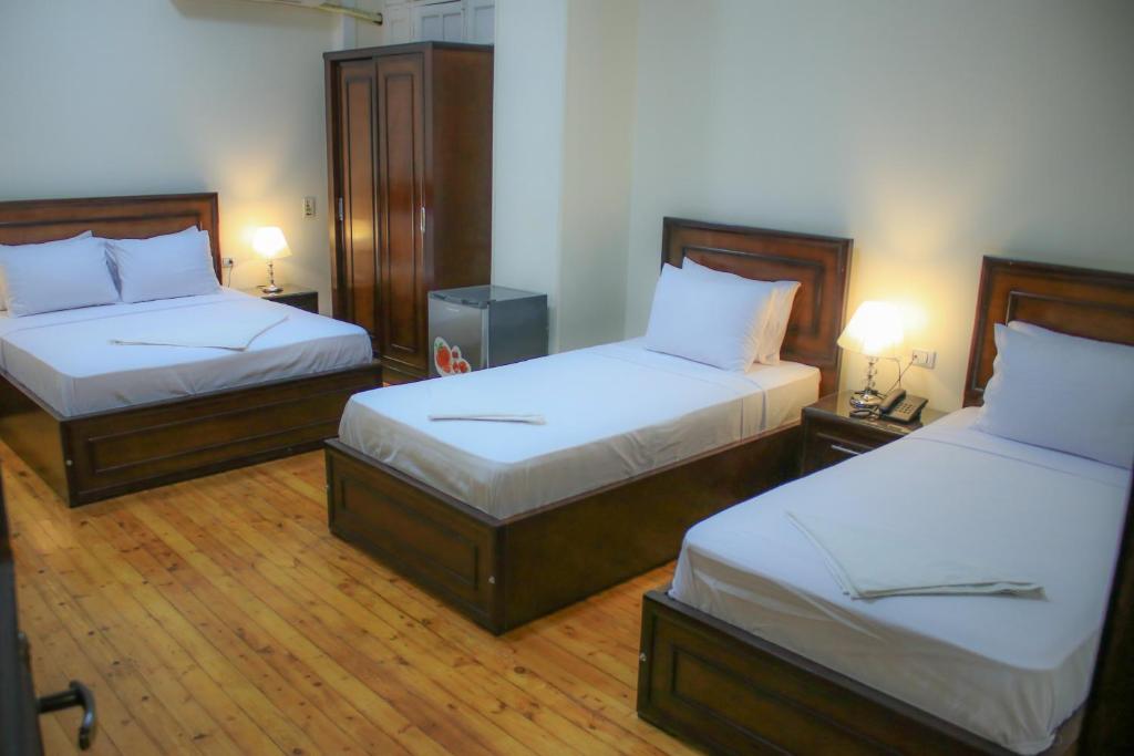 duas camas num quarto de hotel com duas lâmpadas em Kmt Hostel em Cairo