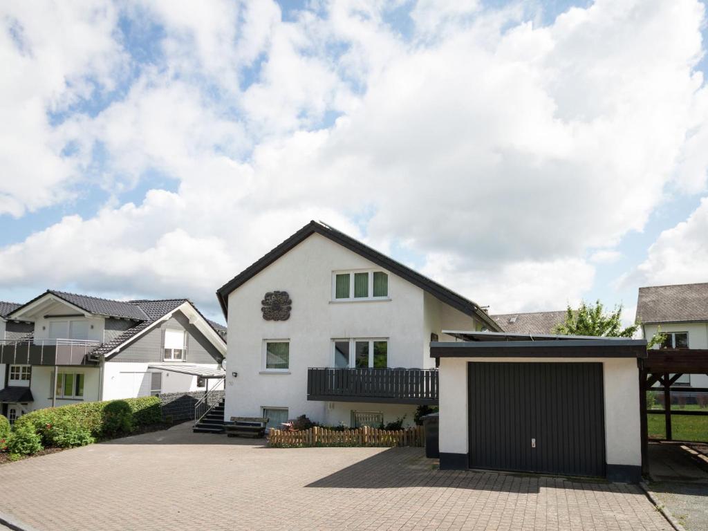 a white house with a black garage at Enchanting Holiday Home in B defeld with Terrace in Schmallenberg