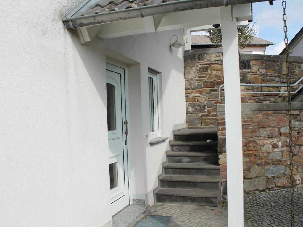 a door to a house with a stone wall and stairs at House with modern interior and garden in the Volcanic Eifel near deer game park in Strotzbüsch