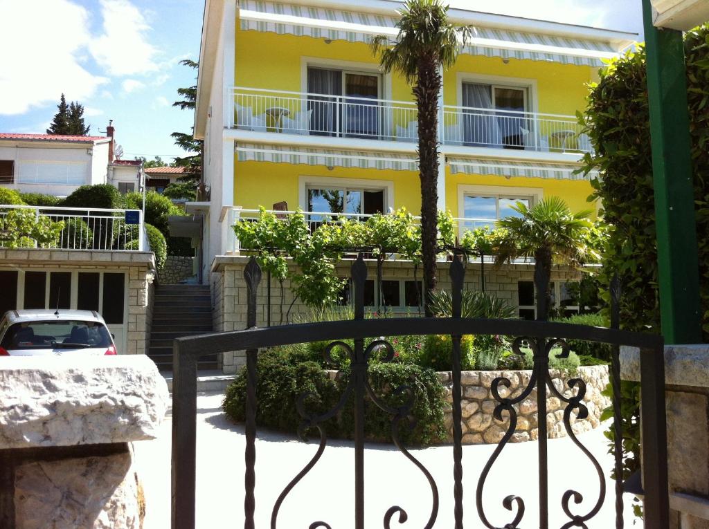 a yellow building with a palm tree in front of it at Apartments & Rooms Marina in Dramalj