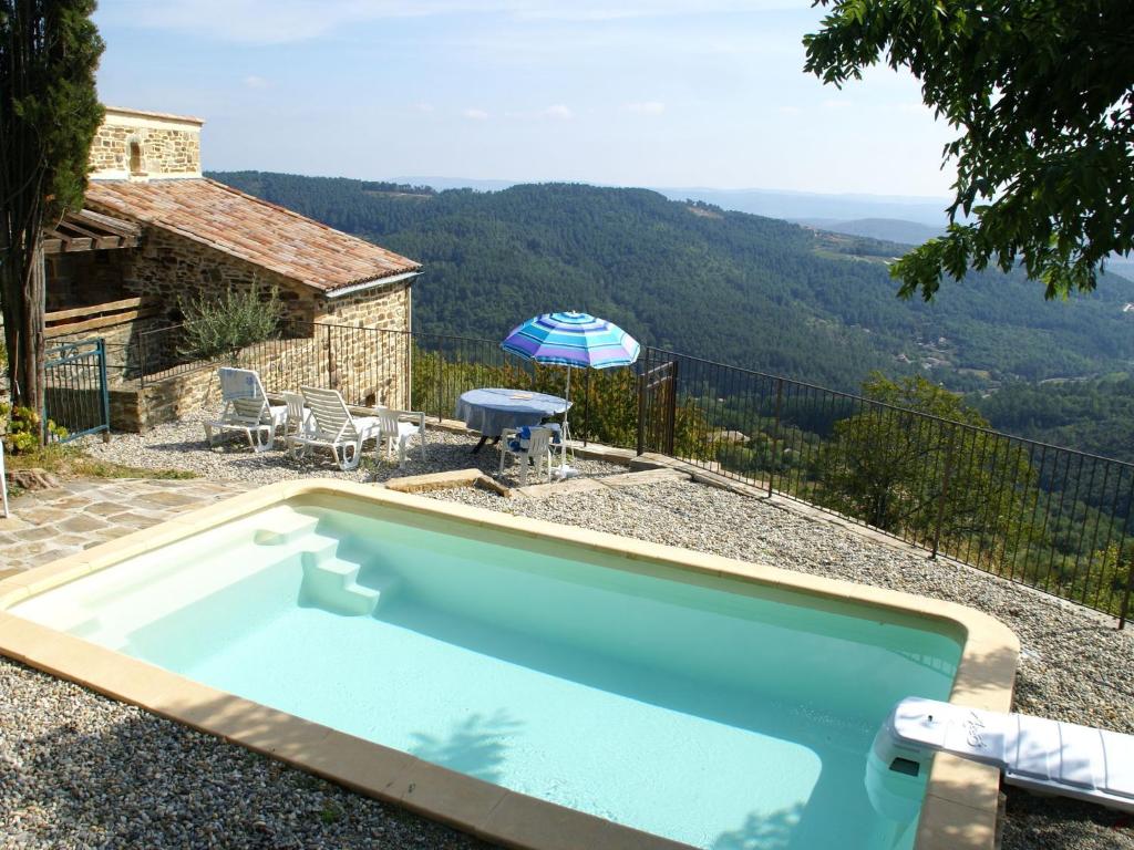 uma piscina com uma mesa e um guarda-sol em Superb holiday home in Chassiers with private pool em Rocher