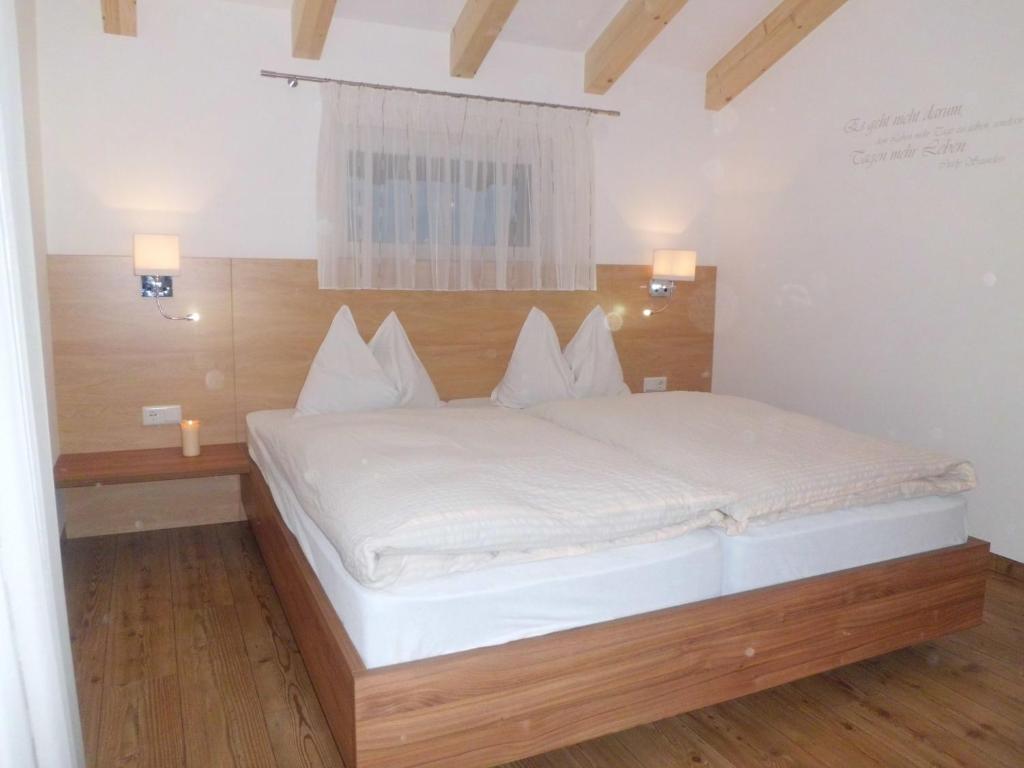 a bedroom with a white bed with a wooden headboard at Appartments Stoanegg in Parcines