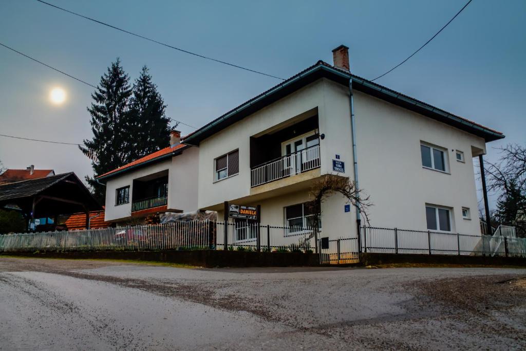 a white house with a fence in front of it at Rooms Daniela in Slunj