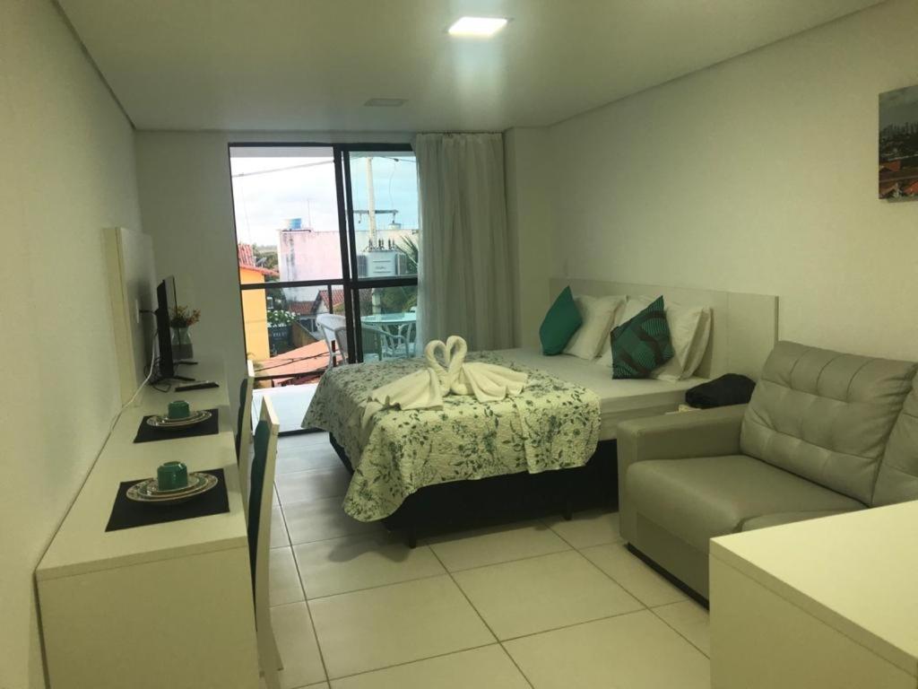 um quarto de hotel com uma cama e um sofá em Laguna Beach Flat em Porto de Galinhas