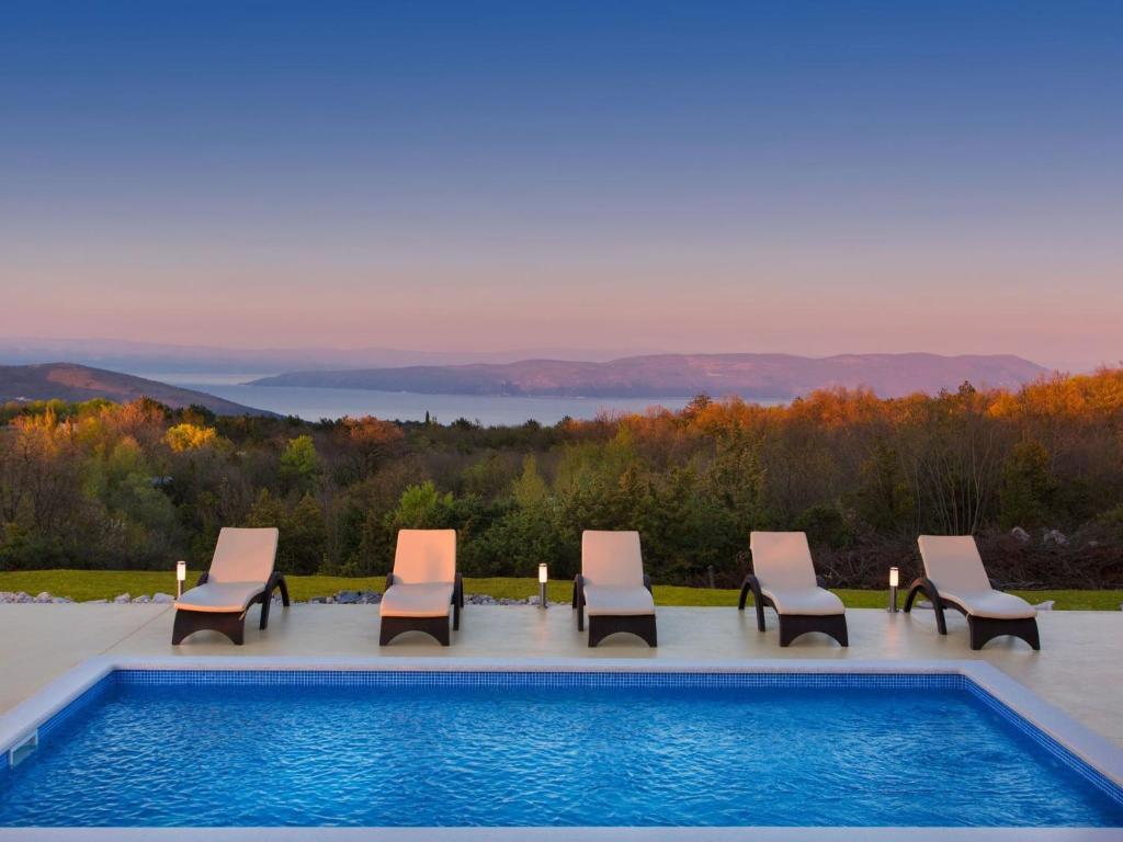 a group of chairs and a swimming pool at Detached villa with private pool located on hill overlooking Kvarner in Hrvatini