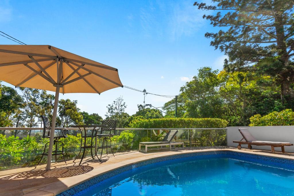 a swimming pool with an umbrella and a table and chairs at Laidback luxury living, Noosa Heads in Noosa Heads