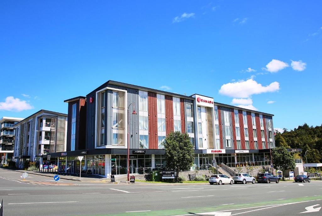 a building on a street with cars parked in front of it at Ramada Suites by Wyndham Albany in Auckland