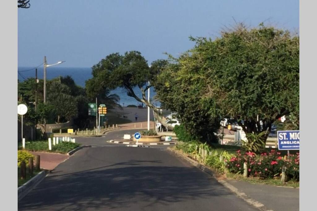 eine leere Straße mit Bäumen und ein Straßenschild in der Unterkunft Close to the sea - Flatlet Umhlanga Rocks in Durban
