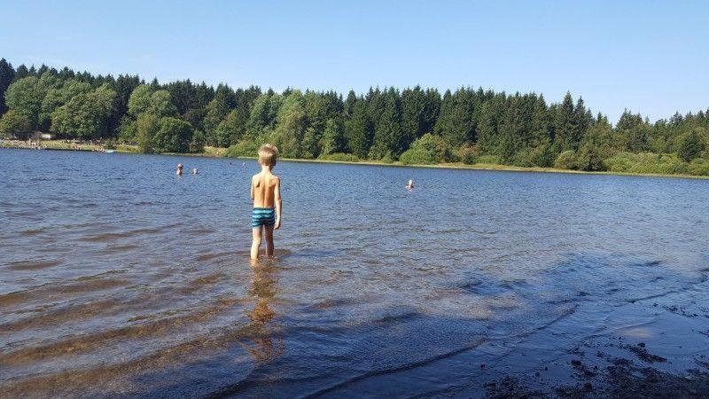 een jongetje in het water bij een meer bij Waldsee-Ferienhaus-mit-Kamin-W-Lan in Clausthal-Zellerfeld